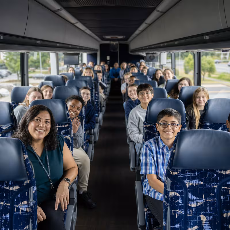 Group boarding a white charter bus for School Transportation transportation in Mobile